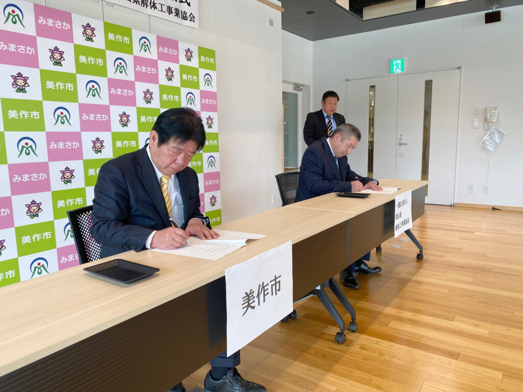 協定書に署名する萩原市長と坂田会長