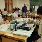 真剣なまなざしで墨絵に挑戦する児童たち=岡山県津山市で