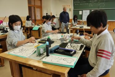 真剣なまなざしで墨絵に挑戦する児童たち=岡山県津山市で