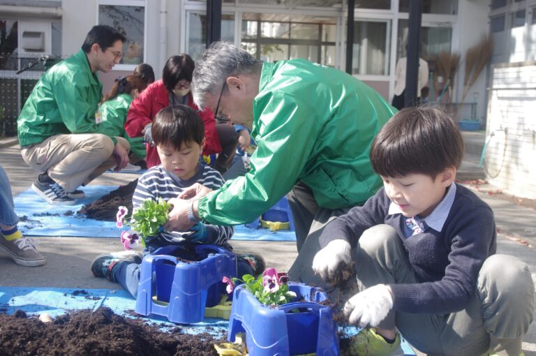 社員に教わりながら花の苗を植える園児=岡山県津山市で