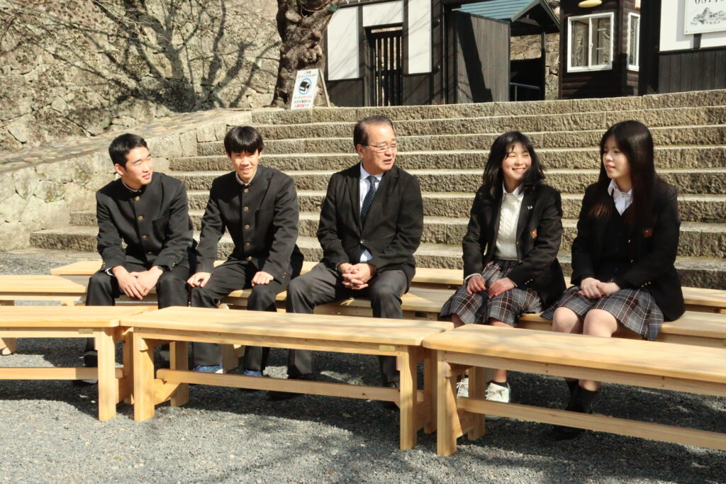 ベンチの座り心地を確かめる高校生と河本観光協会長