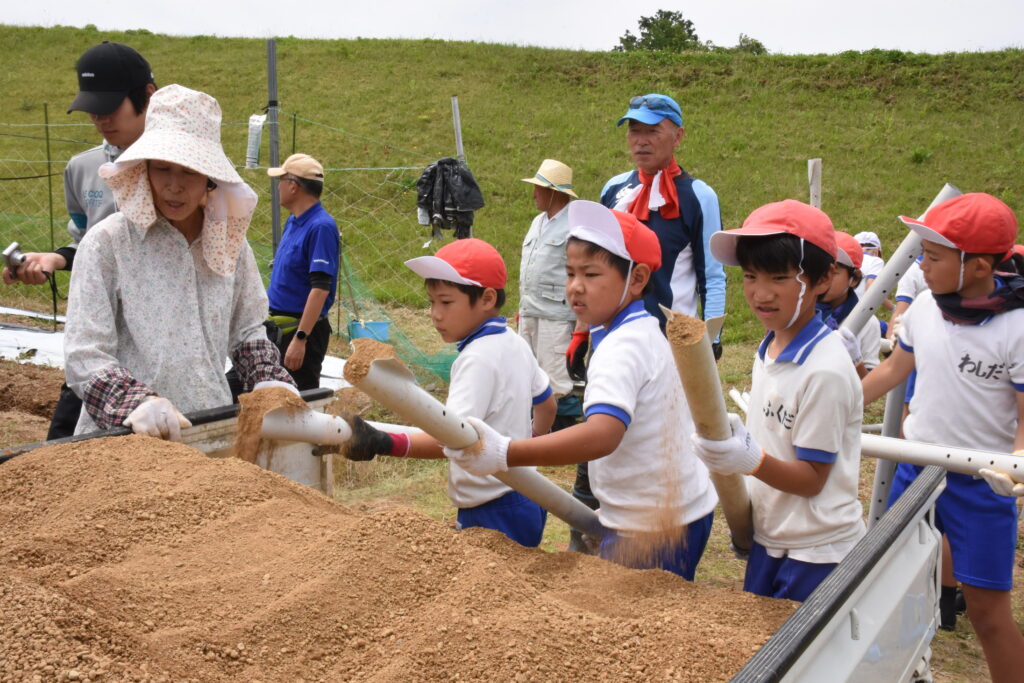 塩ビパイプに“とっこ土”を入れる児童