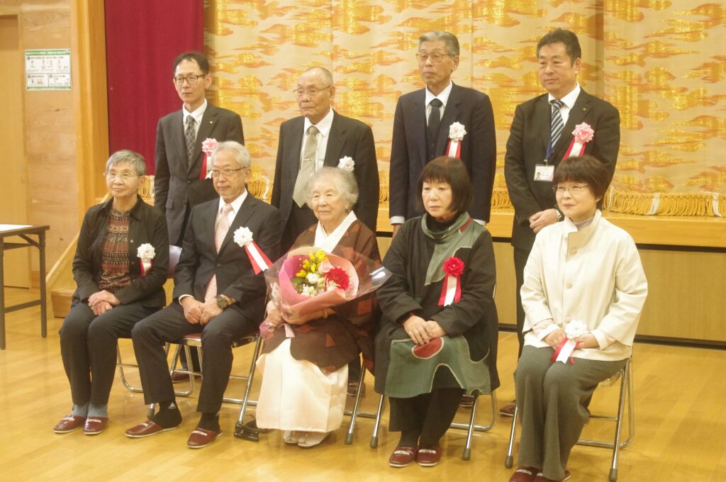花束を手にする頭士さん（前段中央）と江田さん（前段右から２番目）