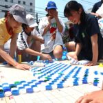 ペットボトルのキャップでモザイクアートを制作する参加者=岡山県津山市で