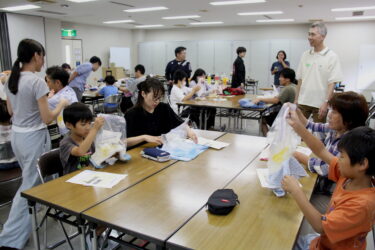 氷と塩を入れた袋を一生懸命もみ、シャーベット作りに挑戦する参加者たち＝岡山県津山市で