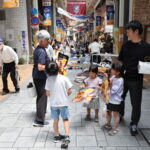 商店街でポスターを配布し上映をPRするファンら