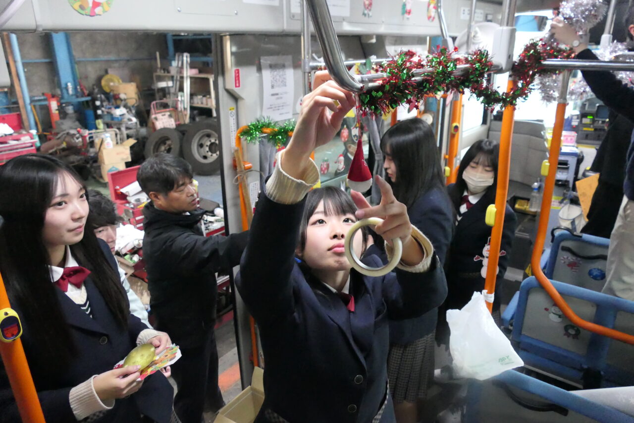 バスの車内を飾りつける生徒たち=岡山県津山市で