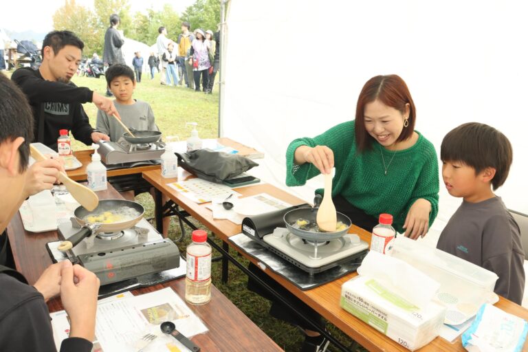 食品メーカーのブースで調理体験を楽しむ親子連れ=岡山県津山市で