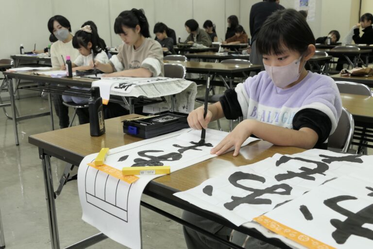 書き初めに挑戦する小中学生たち=岡山県津山市で
