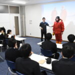 観測隊の防寒着について説明する堀川さん（正面左）=岡山県津山市で