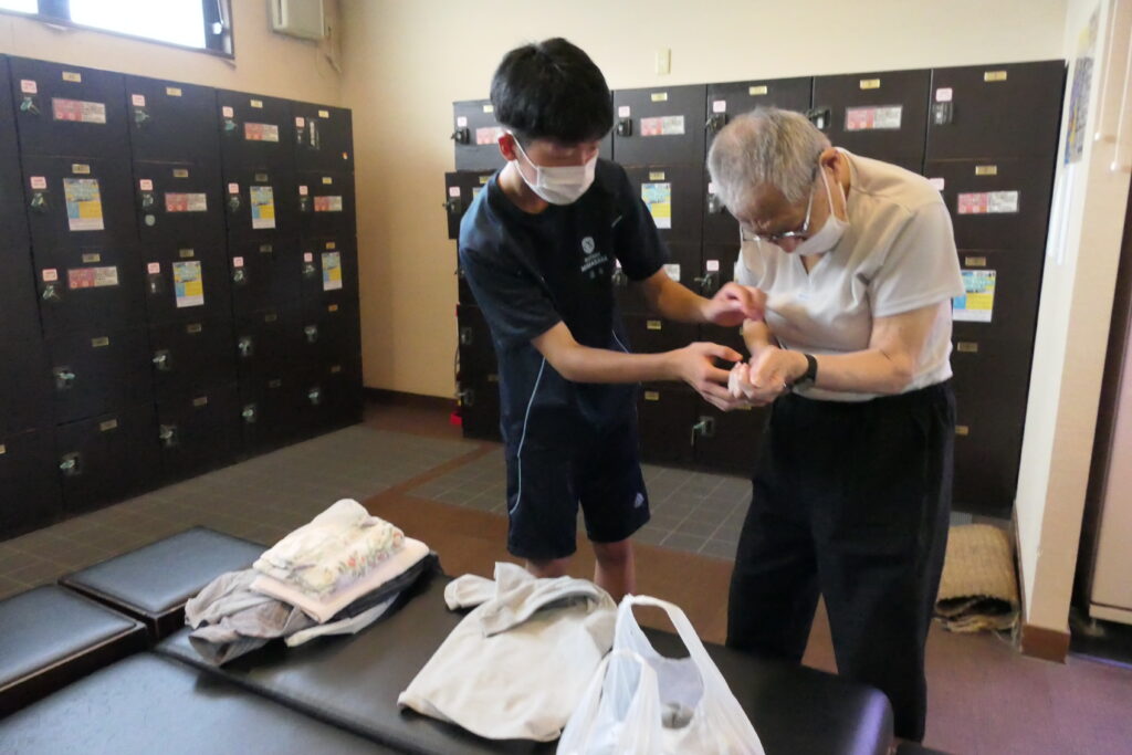 介助してもらいながら入浴準備をするお年寄り