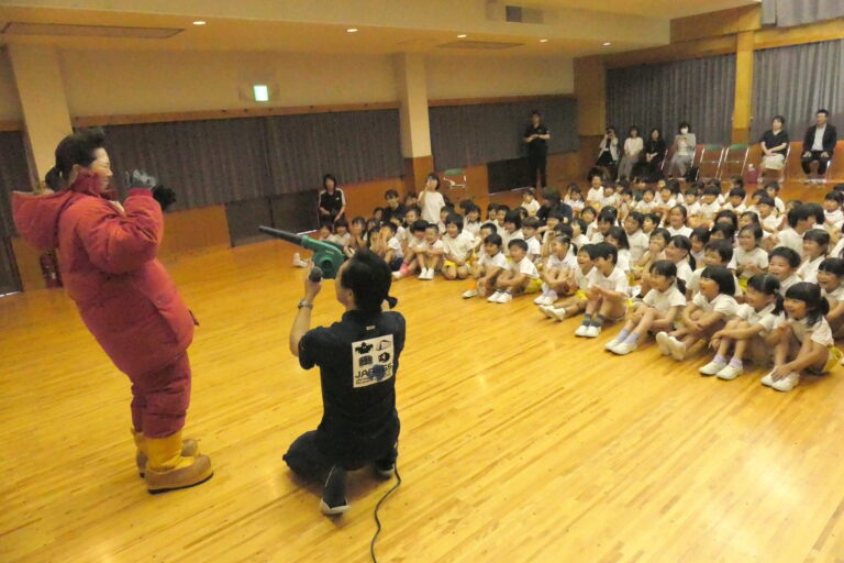 風速60㍍を体感する保育教諭の様子を見守る子どもたち＝岡山県津山市で