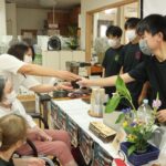 認知症の高齢者らに笑顔でコーヒーを提供する生徒たち=岡山県津山市で