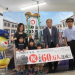 くす玉を割り、来館者60万人達成を祝う桝本さん家族ら＝岡山県津山市で