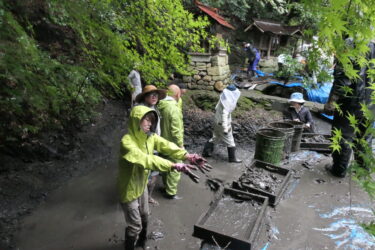 池の中にたまった泥や落ち葉などをかき出す参加者＝岡山県津山市で