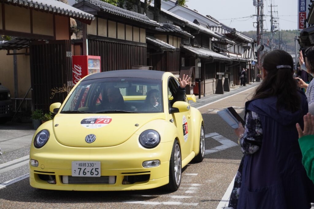 詰めかけたファンや住民らから歓迎を受けるビンテージカー