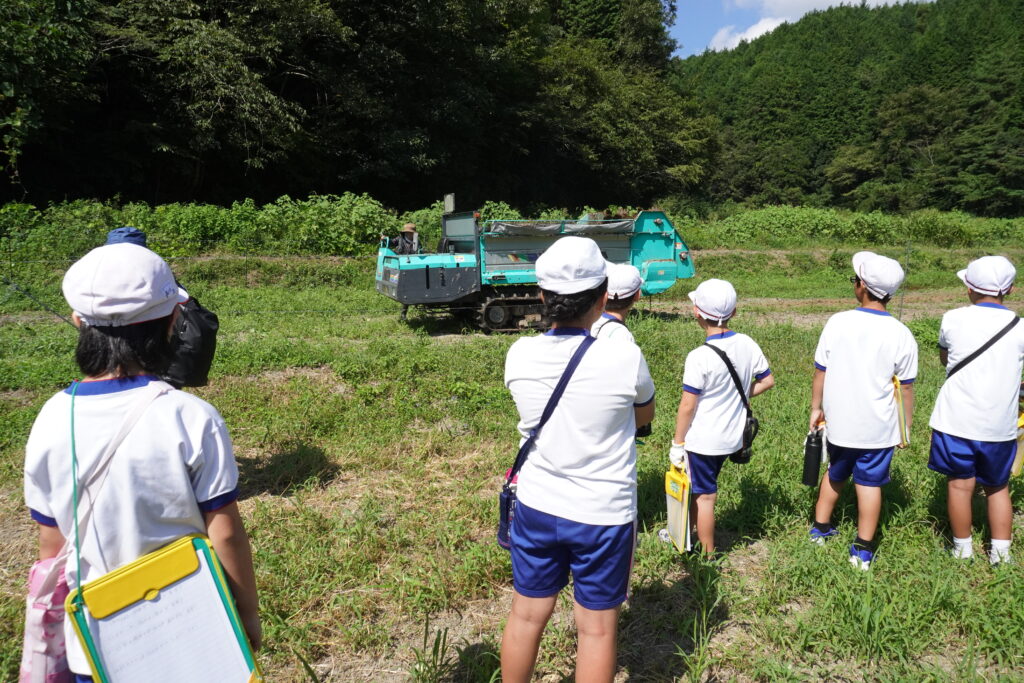 堆肥散布機に興味津々の児童たち