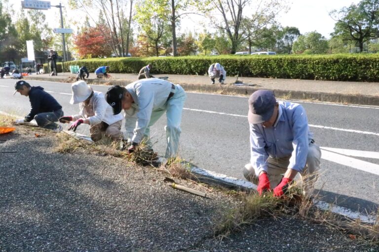 歩道で草取りなどの清掃奉仕をする会員たち=岡山県津山市で