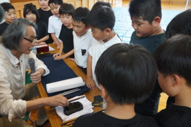 武藤さんから墨のすり方を教わる児童たち=岡山県津山市で