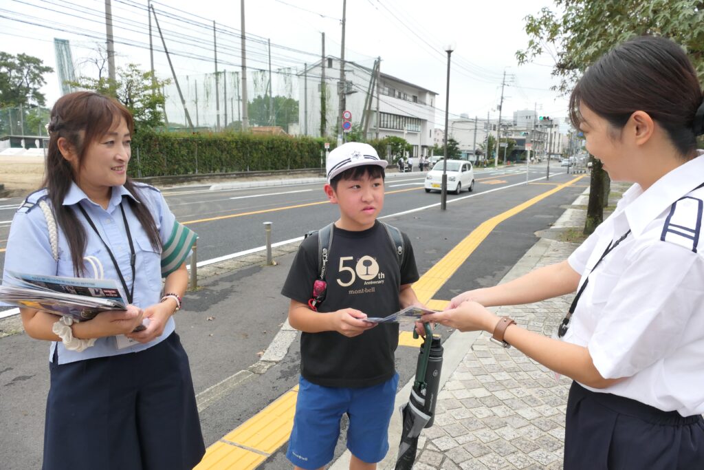 職員からグッズとチラシを受け取る小学生