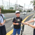 職員からグッズとチラシを受け取る小学生