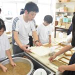 上田さんに教わって紙漉きを体験する子どもたち=岡山県津山市で