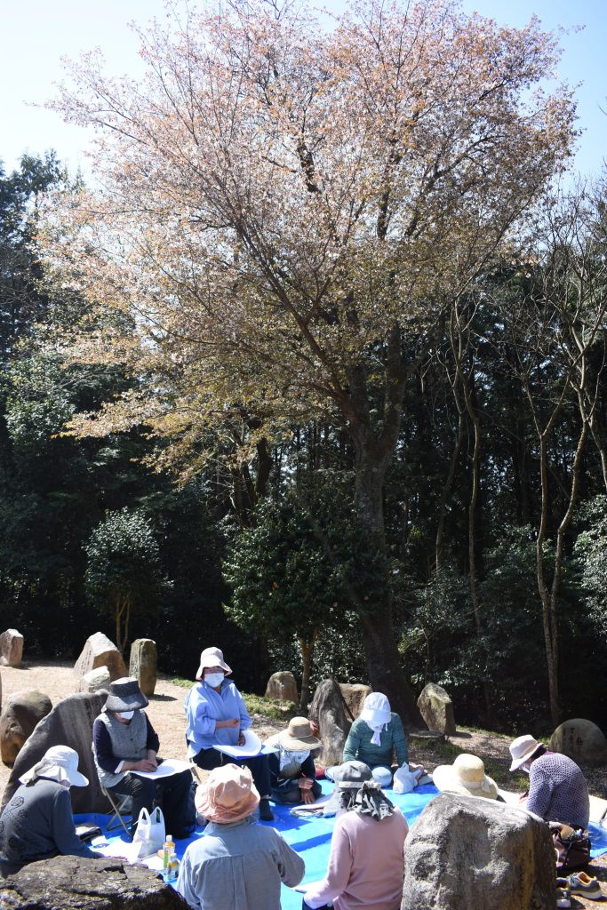 一本桜の花吹雪の中、句を披露し合う門下生たち