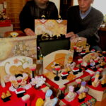 一枚板の夫婦びなを手にする藤原さん夫妻