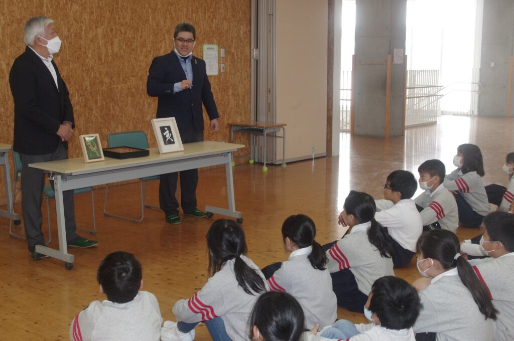 山川会長らの話を聞く児童たち