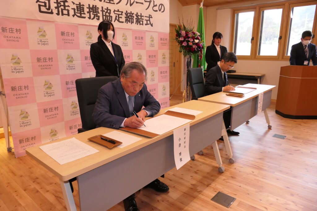 協定書に署名する小倉村長と斎藤社長