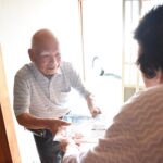 たくさんの服を積んだ車で出発する松本さん