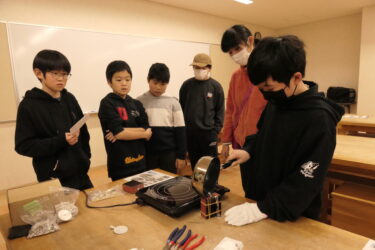 慎重に溶けた金属を鋳型に流す小学生=岡山県津山市で