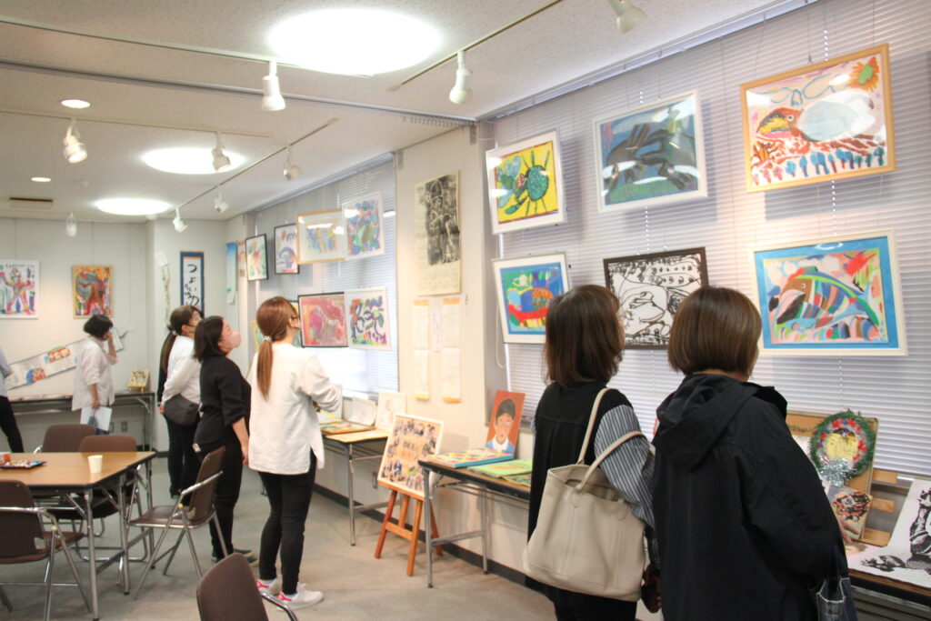 尾崎さんの人柄がしのばれる作品を観賞する来場者