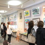 尾崎さんの人柄がしのばれる作品を観賞する来場者