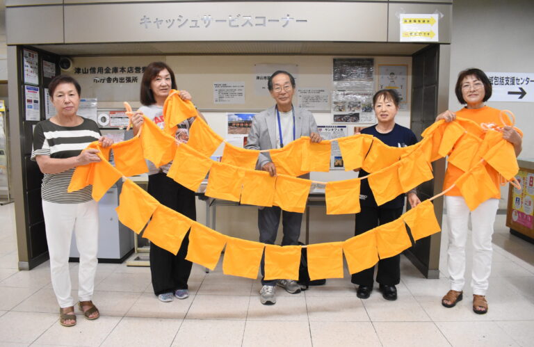 認知症啓発のため手作りしたオレンジ色のガーランドを手にする委員たち＝岡山県津山市で