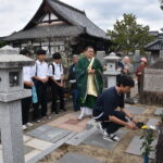 墓前にコーヒーを供え、手を合わせる参加者=岡山県津山市で