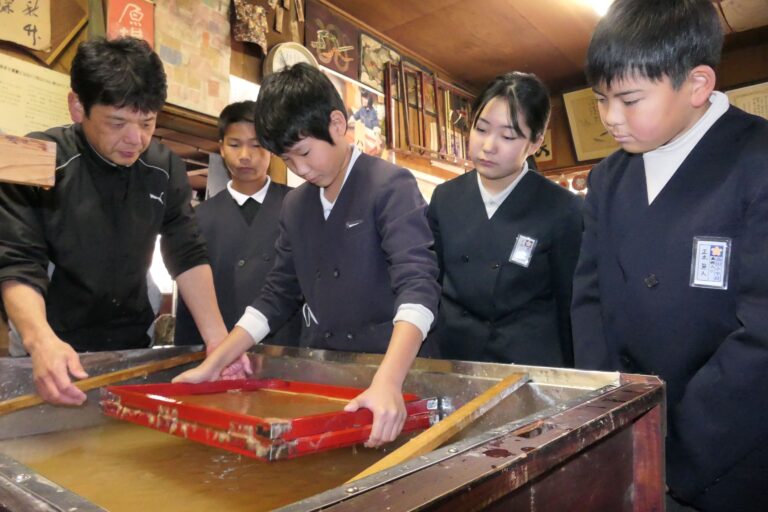 上田さんの指導で卒業証書づくりに励む6年生=岡山県津山市上横野の上田手漉和紙工場で