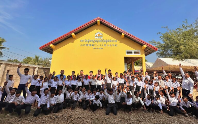 寄贈したカンボジアのマニャプロウ小学校新校舎と児童たち（山田養蜂場提供）