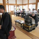 読経が響く中、焼香する会員たち=岡山県津山市で
