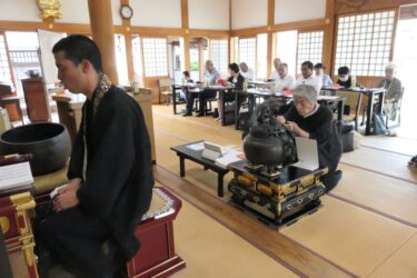 読経が響く中、焼香する会員たち=岡山県津山市で