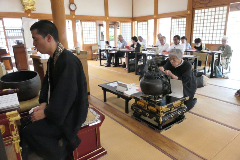 読経が響く中、焼香する会員たち=岡山県津山市で
