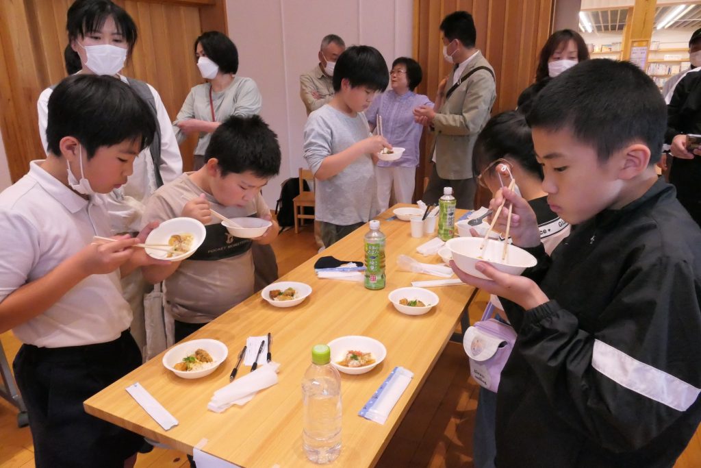 自分たちが考えた料理を試食する小学生