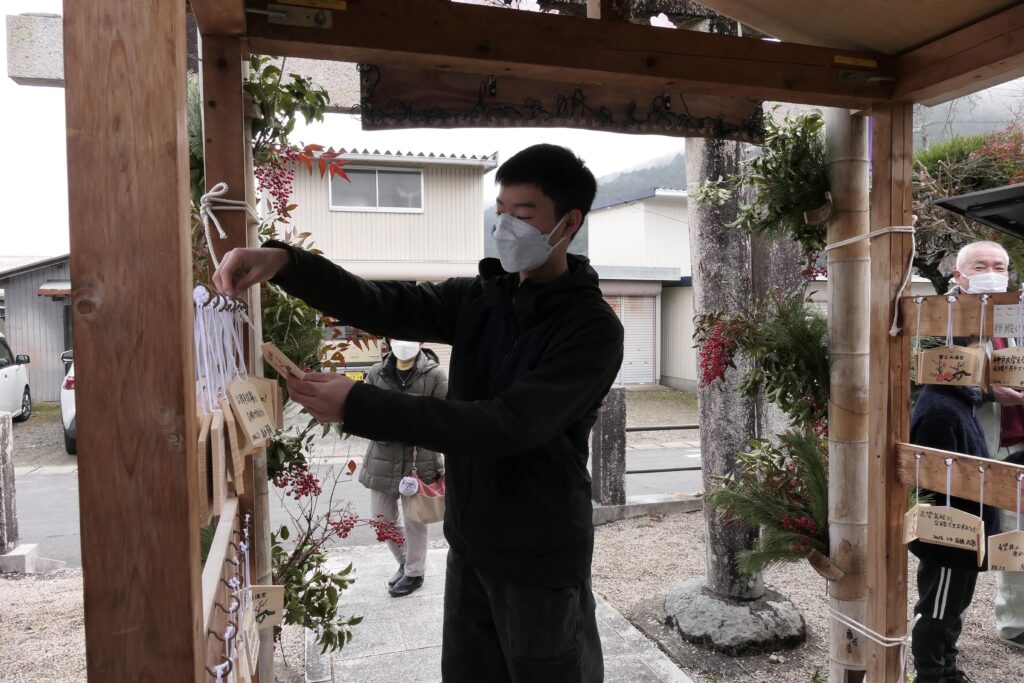 合格門に絵馬をかける参拝者