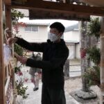 合格門に絵馬をかける参拝者