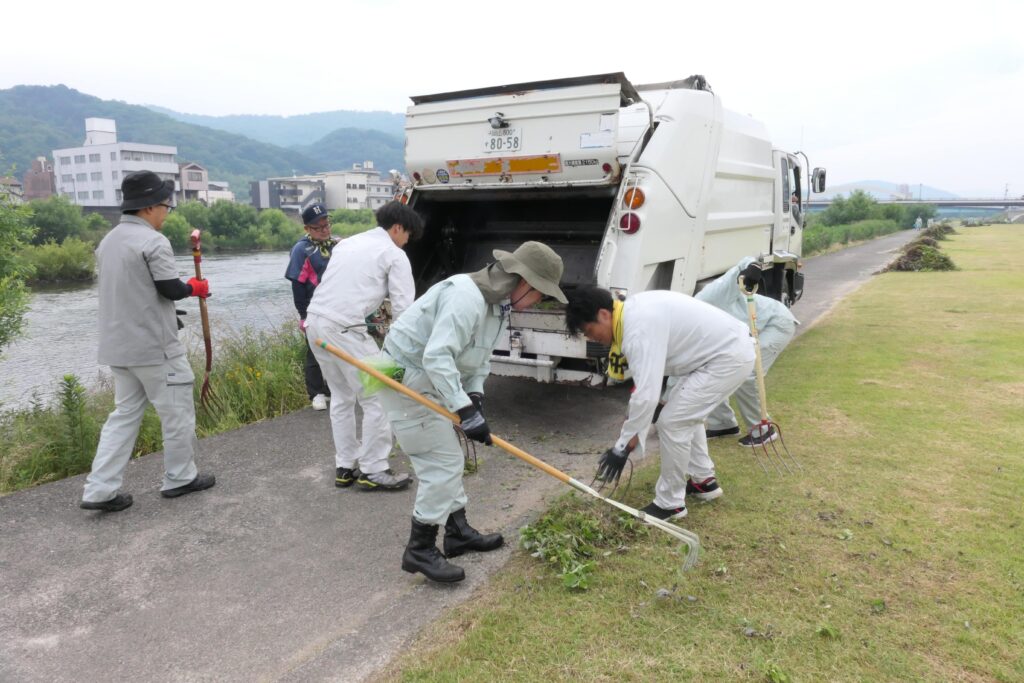 集めた雑草をパッカー車に入れる市民