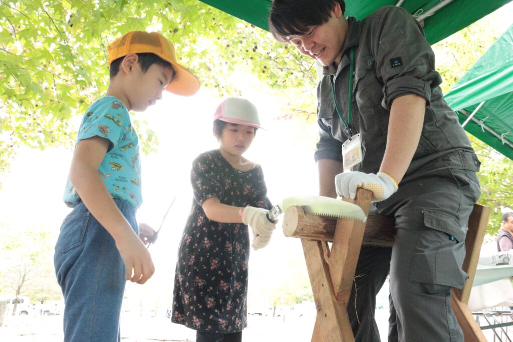 丸太切りを体験する子ども