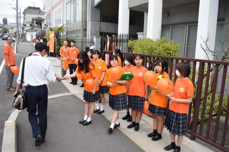 校門前に「オレンジ色」の高校生たち 介護福祉士を目指す生徒らが伝え