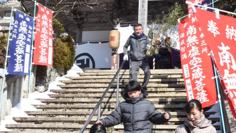 福笹を手に下山する参拝者=岡山県津山市で