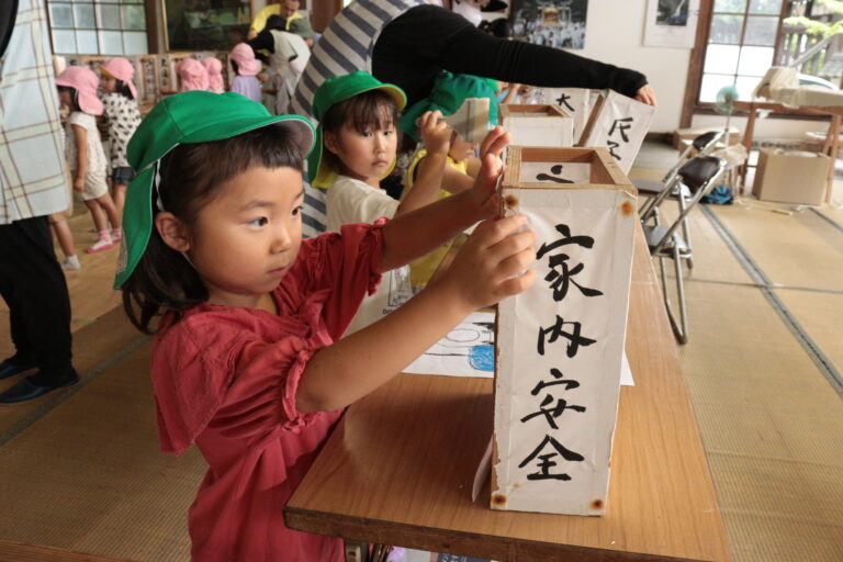 慎重に灯籠に半紙を貼る子ども=岡山県津山市で