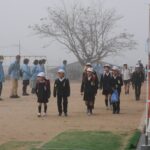 登校する児童にあいさつをする民生児童委員ら=岡山県津山市で